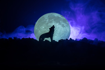 Silhouette of howling wolf against dark toned foggy background and full moon or Wolf in silhouette...