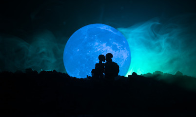 Silhouette of couple kissing under full moon. Guy kiss girl hand on full moon silhouette background. Valentine`s day decor concept. Silhouette of loving couple kissing against the moon