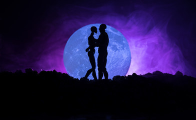 Obraz na płótnie Canvas Silhouette of couple kissing under full moon. Guy kiss girl hand on full moon silhouette background. Valentine`s day decor concept. Silhouette of loving couple kissing against the moon