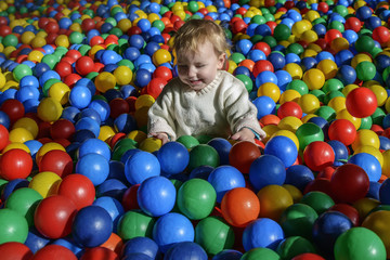 Fototapeta na wymiar happy little child plays on a playground filled with colorful plastic balls.