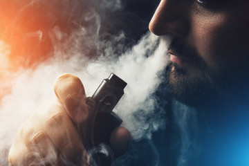 Man vape e-cigarette with e-liquid, close-up, breathes out large cloud of steam or vapor. Vaping...