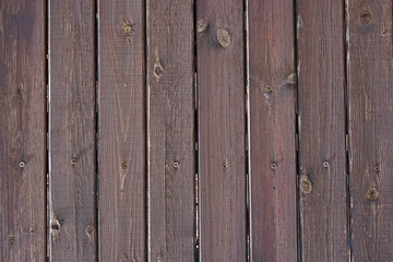 Texture of an old brown wooden fence. Peeling brown paint on weathered wood texture. Old wood boards, vintage background.