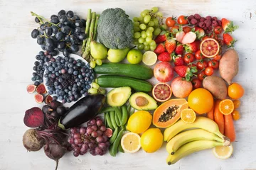 Fotobehang Groenten Healthy eating concept, assortment of rainbow fruits and vegetables, berries, bananas, oranges, grapes, broccoli, beetroot on the off white table arranged in a rectangle, top view, selective focus  © Liliya Trott