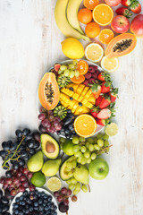 Fototapeta na wymiar Healthy eating background, assortment of fruits and vegetables in rainbow colours on the off white table arranged diagonally, copy space, vertical, top view, selective focus