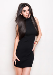 Naklejka premium beautiful young woman with long black hair posing in black knit dress