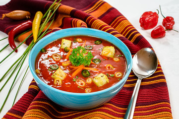 Spicy chili hot tomato soup with bread cubes in a bowl.