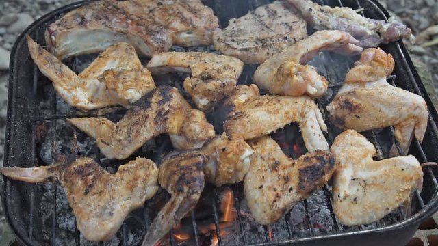 Chicken wings and legs cooking on a barbecue grill, closeup. Outdoor cooking.
