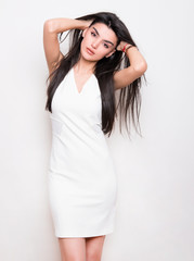 Naklejka premium beautiful young woman with long black hair posing in white dress