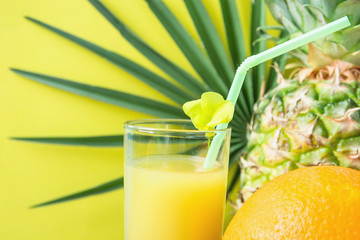 Close up of Tall Glass with Freshly Pressed Pineapple Orange Coconut Juice Straw and Small Flower. Round Palm Tree Leaf on Yellow Background. Vacation Summer Relaxation Travel Healthy Superfoods
