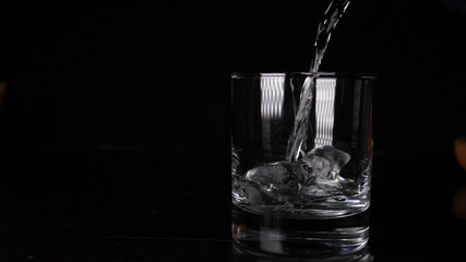 Glass with soda water (bubbles), black background.	