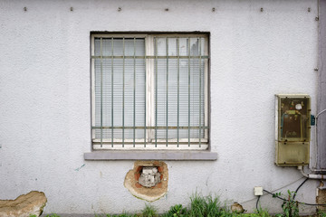 Alter Stromverteiler am vergitterten Fenster / Ein vergittertes Fenster eines baufälligen...