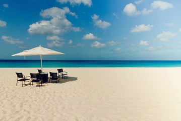 Idyllic caribbean landscape with table, chairs and a parasol in Aruba.