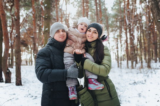 Portrait of Young family and his baby in a winter forest. Beautiful daugther. Happy family.