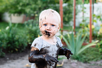 child playing in the mud on the street