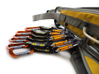 Climbing quickdraws clipped to a harness isolated on white background.