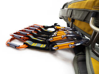 Climbing quickdraws clipped to a harness isolated on white background.