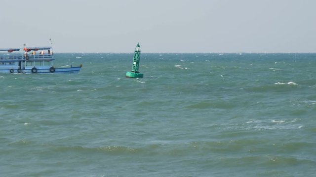 Blue buoy in the sea is sailing by a passenger ferry