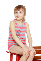 The girl is sitting on a large toy wooden car.