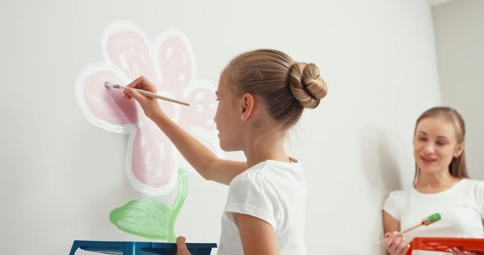 Girl drawing flower on the wall and laughing at camera