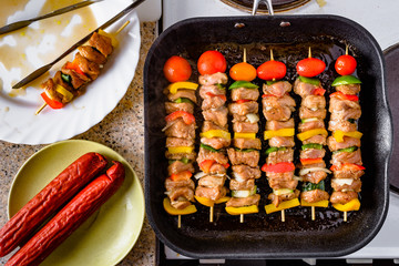 Grilled skewers on wooden sticks, pork meat and vegetables on grill.