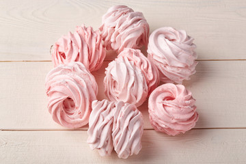 Pink sweet homemade airy zephyr or marshmallows on wooden background