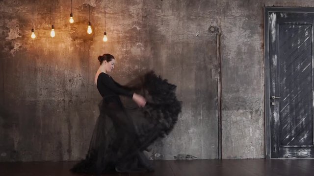 a young and pretty woman choreographer dances in the studio, the lady is dressed in a puffy skirt that flutters because of the elegant movements of the dancer