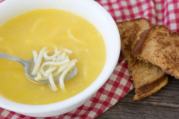 white glass bowl of noodle soup with a sandwhich