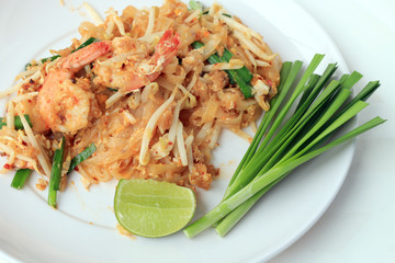 Pad Thai, stir-fried rice noodles with shrimp in white plate with slide lemon and green vegetable. The one of Thailand's national main dish. the popular food in Thailand. Thai Fried Noodles