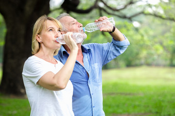 Portrait senior couple standing drinking water at the park