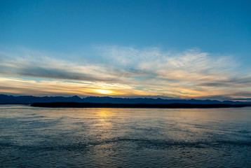 Sunrise on Glacier Bay with coastline, ocean, sky, and clouds