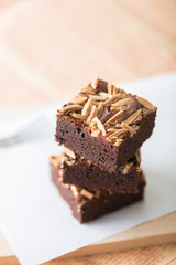 Close up sweet chocolate brownie with almond topping, selective focus