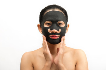 Young woman doing facial black mask sheet with purifying mask on her face on white background