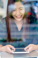 Closeup Asian businesswoman hand using the technology smart tablet with happiness action on the desk beside the glass in workplace or co-working space or modern office, business lifestyle concept
