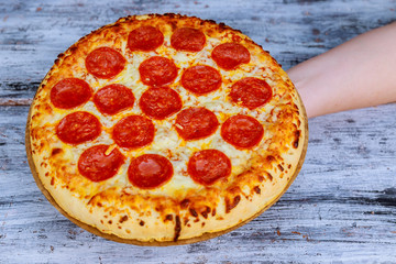 Hot Homemade Pepperoni Pizza on a rustic wooden table. Pizza with tomato,