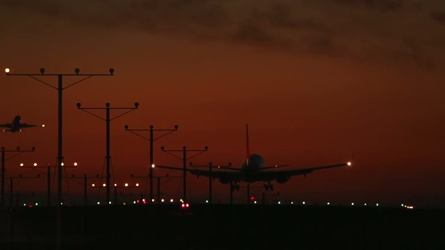 Telephoto shot of plane landing on runway at sunset