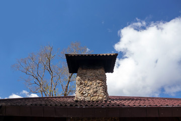 The Gable of a brick house with brick chimney in bright sunlight, against a deep blue sky.