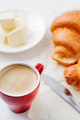 morning coffee in a red cup, croissants and butter on white background