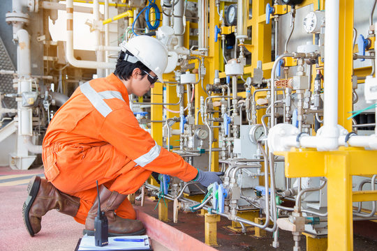 Production Operator Adjust Flow Rate Of Corrosion Inhibitor Pump As Panel Man Command By Radio And Record Data To Logbook, Offshore Oil And Gas Activity At Wellhead Remote Platform.