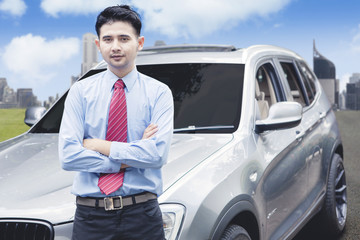 Successful businessman taking photo in front of luxurious car