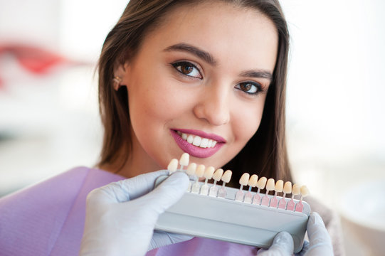 Dentist checking and selecting color of young woman's teeth.