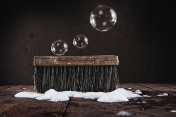 Old vintage scrub brush with bubbles and soap on a wooden floor