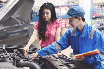 Fototapeta na wymiar Car mechanic helping a customer fixing the car while holding a checklist