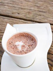 Cup of cocoa with foam on wooden table
