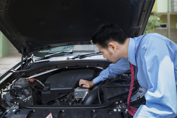 Fototapeta na wymiar Asian businessman checking the engine of a damaged car