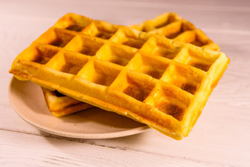Ceramic plate with belgian waffles on wooden table
