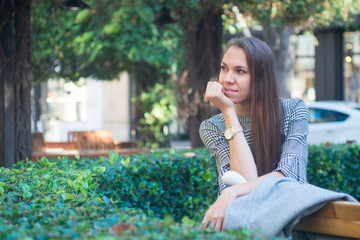 Fototapeta premium Smiling happy woman sitting on the bench in the city