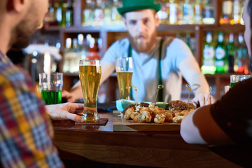 Traditional celebration of Saint Patricks Day: group of friends gathered together in pub, drinking fresh beer and chatting with each other