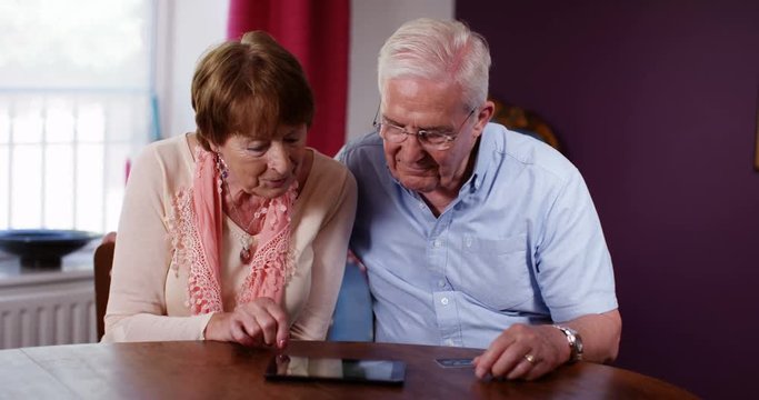 4k, A senior couple using a digital tablet at home.