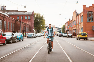 Handsome hipster enjoying city ride by bicycle.