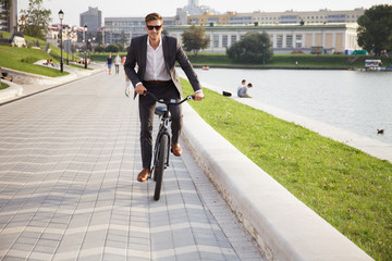 Businessman riding bicycle to work on urban street in morning.